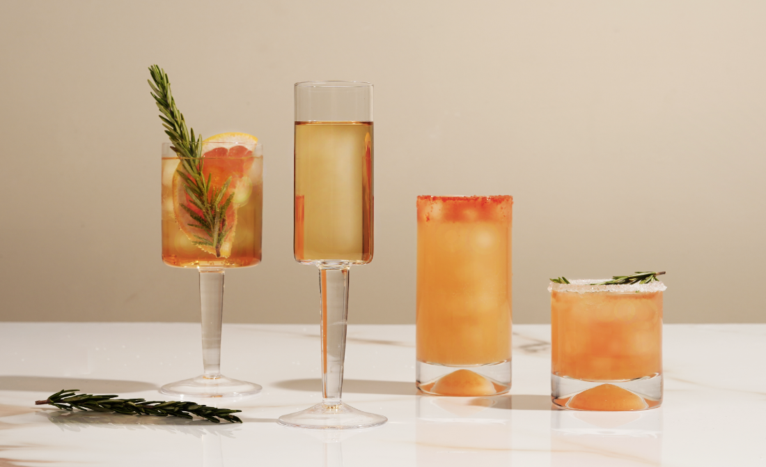 Stylish metal bar cart with glass shelves holding various decorative items and drinks, placed against a wall with framed artwork