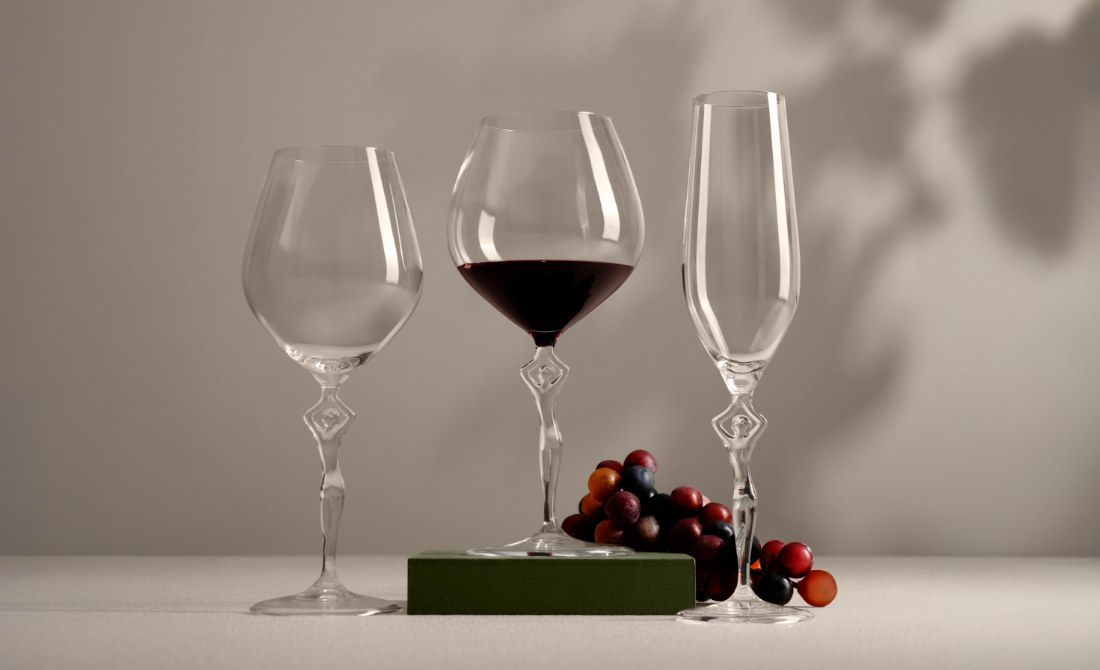 Collection of black bottles and containers with white artistic designs, including hand wash, lotion, hand sanitizer, and a candle, set against a neutral background.