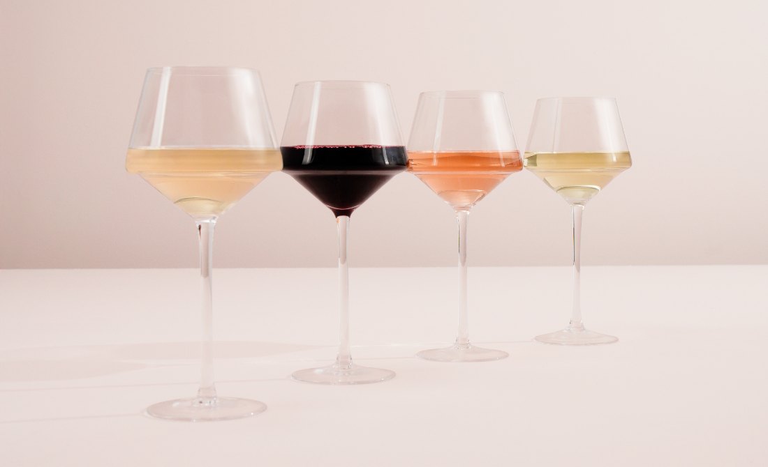 Collection of black bottles and containers with white artistic designs, including hand wash, lotion, hand sanitizer, and a candle, set against a neutral background.