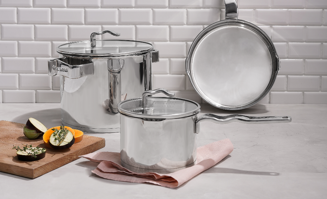 Collection of black bottles and containers with white artistic designs, including hand wash, lotion, hand sanitizer, and a candle, set against a neutral background.