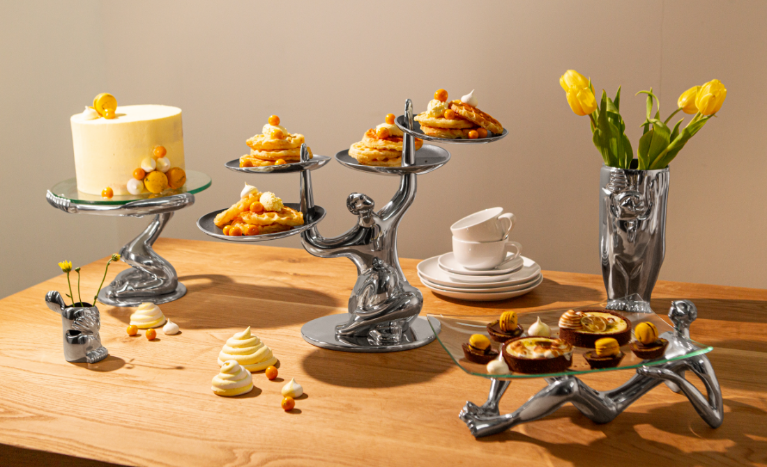 Artistic table setting with ceramic dinnerware featuring face sketches, polished metal serving bowls