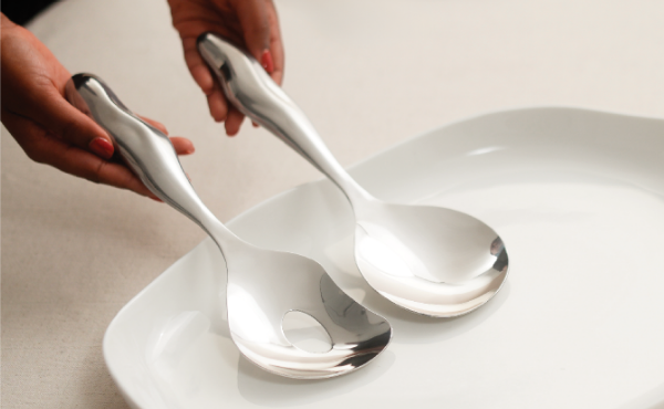 Collection of black bottles and containers with white artistic designs, including hand wash, lotion, hand sanitizer, and a candle, set against a neutral background.