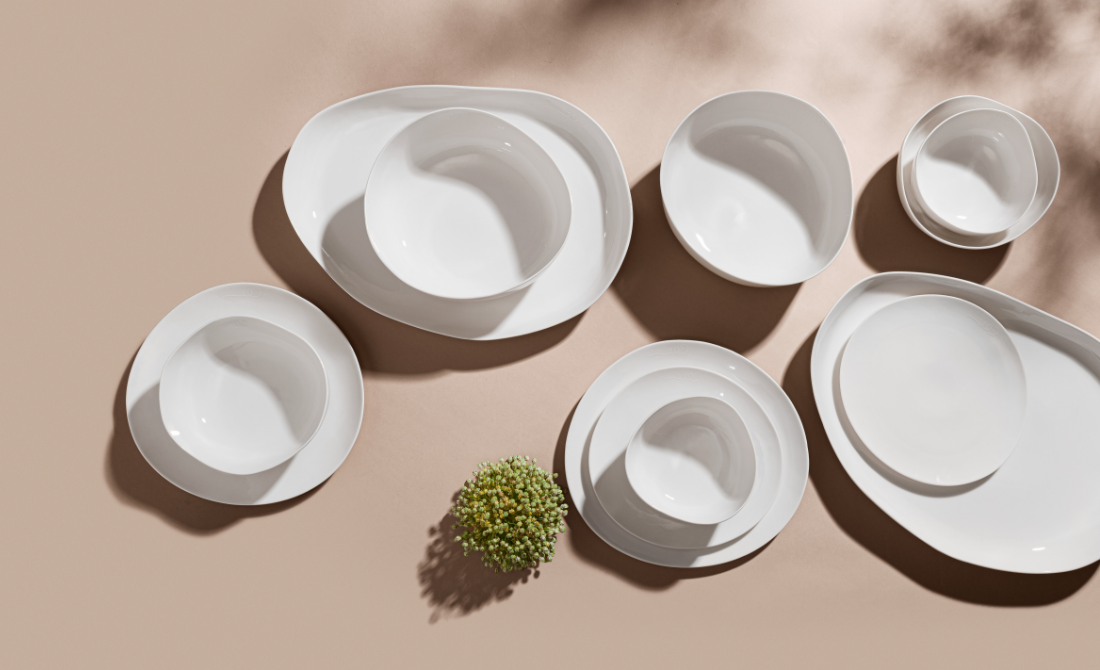 Elegant table setting with white ceramic dishes, polished silverware, glassware, and succulents in bowls.