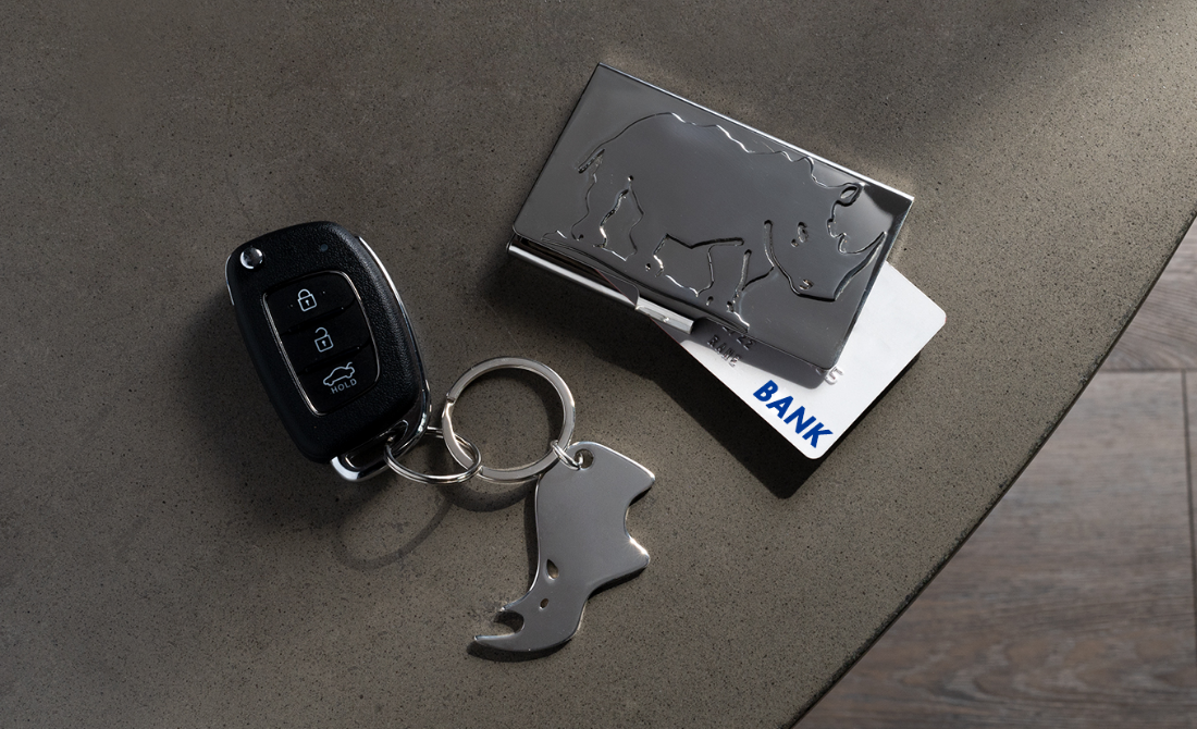 Polished silver serving utensils and a small bowl with chocolates, accompanied by a glass, set against a green background.