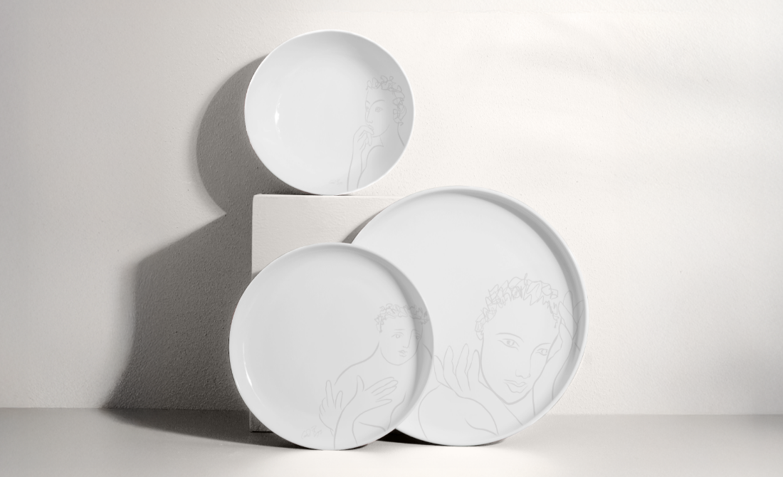 Collection of black bottles and containers with white artistic designs, including hand wash, lotion, hand sanitizer, and a candle, set against a neutral background.